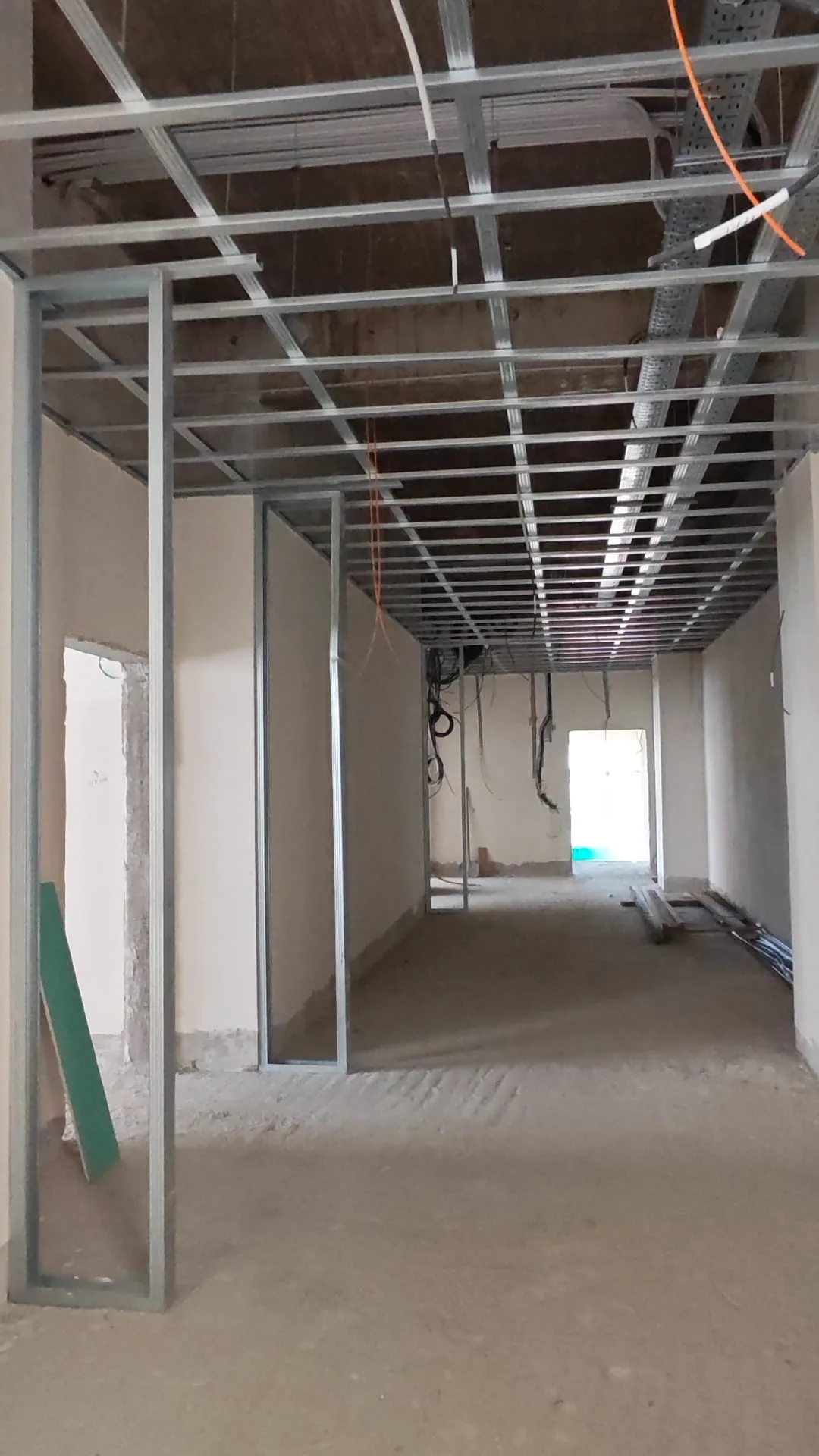Echipă montând placă de gips-carton pe structură, lucru în echipă